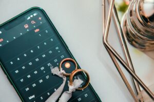 Configuración elegante de anillos de boda en un smartphone mostrando una fecha en el calendario, simbolizando planificación y celebración.