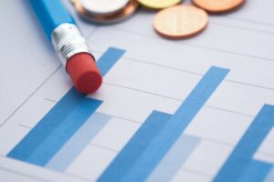 Primer plano de gráficos de barras con un lápiz y monedas, simbolizando análisis financiero.