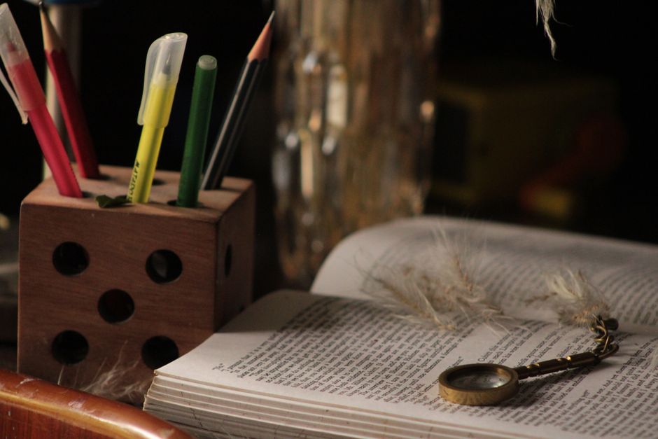 Una escena de estudio cálida y acogedora que presenta un libro abierto, una lupa y lápices de colores.